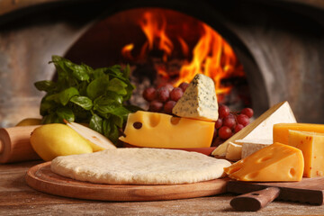 Fresh ingredients for pizza on wooden table against oven
