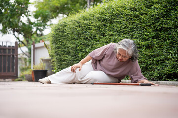 Senior Asian Woman Falling Down Outdoors Due to Accident or Weakness, Accidental Fall of a Mature Woman on a Paved Path, Elderly Woman Collapses While Walking, Needing Assistance
