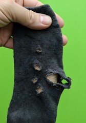Obraz premium Grungy Old Sock with Holes Held in Hand – Minimal Background