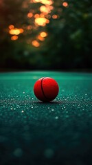 Red ball rests, on a textured surface, against soft bokeh, glowing at sunset's fading light