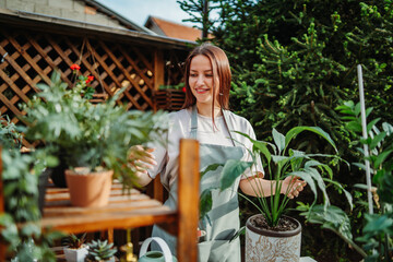 Young woman taking care of plants with water can and mister	