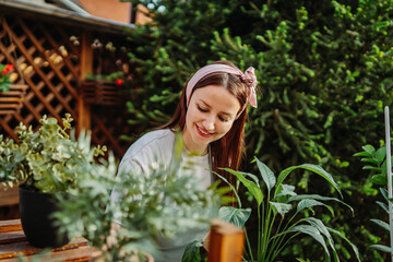 Young woman taking care of plants with water can and mister	