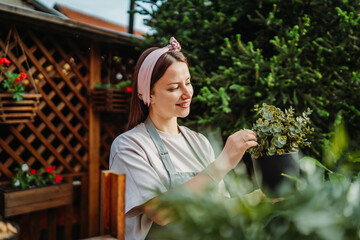 Young woman taking care of plants with water can and mister	
