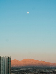 Full moon over desert mountain at sunset, Las Vegas skyline with pastel sky, serene evening landscape with city and mountains, minimal moonrise photography, urban desert scene