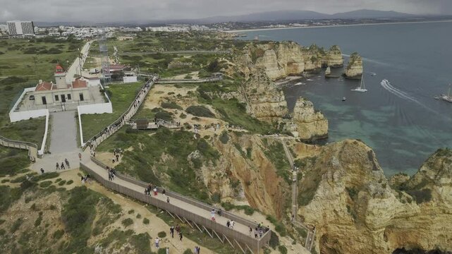 Drone flies north over Ponta da Piedade and the plethora of winding trails down to beaches and rock formations along the coast in Lagos, Portugal