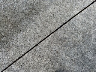 Obraz premium Closeup of textured gray asphalt surface with a dark rubber crack running through it. Urban pavement detail background.