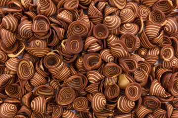 A top-down full frame view of numerous "Kuping Gajah" Indonesian traditional cookies. These crispy, thin cookies are characterized by their distinctive spiral pattern of light and dark brown.