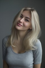Fototapeta premium A woman with blonde hair and a large bust is wearing a gray shirt