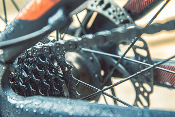 Bike gears with water droplets on the rear derailleur. Close-up of bicycle cassette covered in rain. Water drops on bike cassette and chain close-up. Mountain bike cassette with wet details and chain