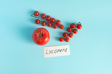 Red tomatoes and cherry tomatoes in close-up on a pink background the inscription lycopene as the main antioxidant in tomatoes