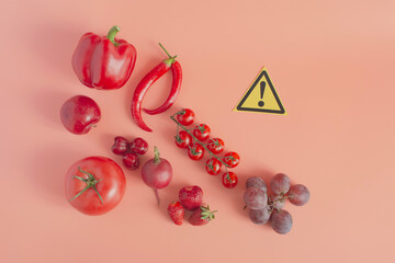 Red vegetables fruits and berries sweet peppers, hot peppers and cherry tomatoes strawberries grapes and a close-up sign on a pink background