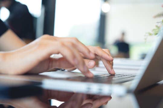 Business woman hands typing on laptop computer, browsing the internet, remote working at coffee shop with blurred background. Woman using laptop for social network at home, business casual