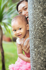 Asian mother and toddler girl happy playing peek a boo  or hide and seek together