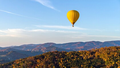 Naklejka premium Vibrant yellow hot air balloon gliding above serene autumn mountain landscape