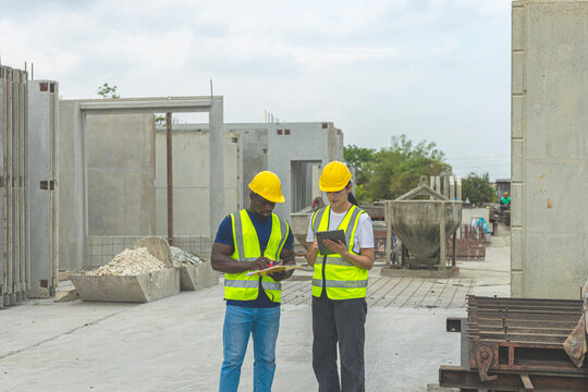 Two civil engineers from different cultures and ethnicities working together in a precast factory. Workers using tablet and walkie talkie in a factory production system. Gender in a factory
