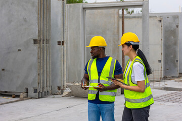 Two civil engineers from different cultures and ethnicities working together in a precast factory. Workers using tablet and walkie talkie in a factory production system. Gender in a factory