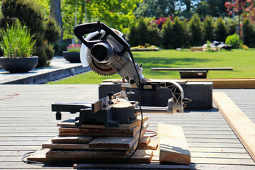 Male carpenter using electric circular saw in home workshop with wood chips flying