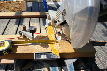 Male carpenter using electric circular saw in home workshop with wood chips flying