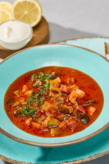 Vibrant Meat Solyanka Soup with Olives in Rustic Setting