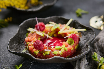 Tuna and avocado tartare with raspberry sauce, moody lighting, gourmet composition