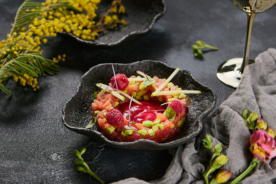 Tuna and avocado tartare with raspberry sauce, dramatic lighting, vibrant color contrast, elegant plating