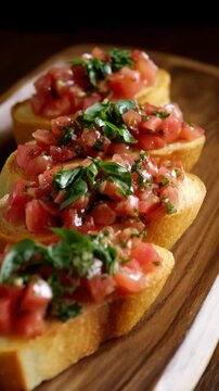 Close up of toasted baguette slices topped with fresh diced tomatoes and basil on a rustic wooden board, food photography.