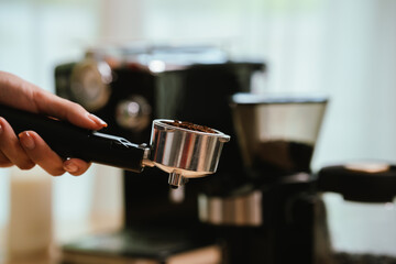 Barista grinding coffee beans and pouring espresso from machine in café, showing close-up of professional preparation of hot aromatic drink.