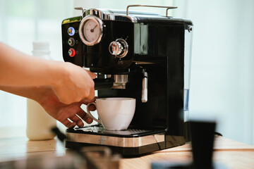 Barista grinding coffee beans and pouring espresso from machine in café, showing close-up of professional preparation of hot aromatic drink.