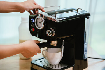 Barista grinding coffee beans and pouring espresso from machine in café, showing close-up of professional preparation of hot aromatic drink.