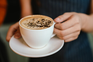 Barista grinding coffee beans and pouring espresso from machine in café, showing close-up of professional preparation of hot aromatic drink.