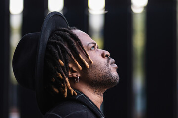 Pensive black man in hat looking up