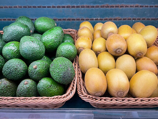 Fresh organic Avocados and Golden kiwi in basket for selling in the supermarket.