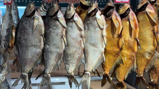 Front view of several dried fish hanging at a market stall. The image captures traditional food preservation methods, rich textures, and the authentic atmosphere of a local fish market