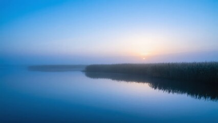 Fototapeta premium Sunrise Over a Calm Lake with Foggy Forest Reflection