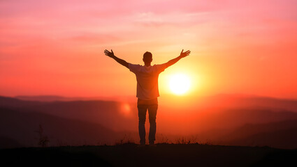 Fototapeta premium Embracing the Dawn: A silhouetted figure stands with arms outstretched, absorbing the golden light of a sunrise, a testament to hope, resilience, and the boundless beauty of nature. 