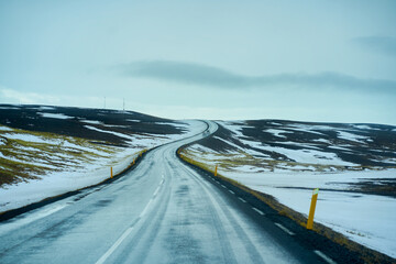Road trip with uphill road landscape in winter at Iceland. Asphalt road with sideways full of snow