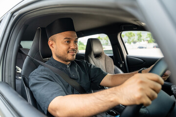 Asian muslim business man getting new car. Happy and excited. Smiling man islamic driving vehicle on the road wearing songkok cap. Businessman buying driving new car
