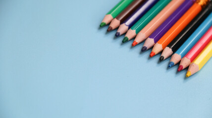 Various colored pencils isolated on blue background. copy space