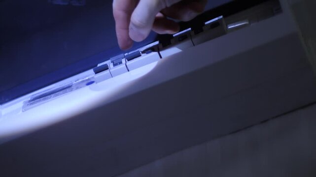 Man’s hand in darkness turns on circuit breaker in electrical box at home, bottom view—electrician restores power by activating automatic switch