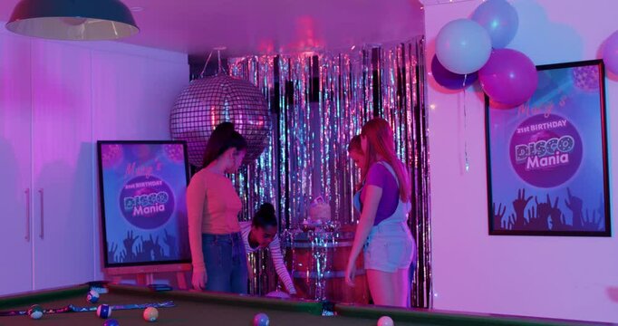 Planning Disco Mania Diverse female friends decorating game room with cake under disco ball dancing