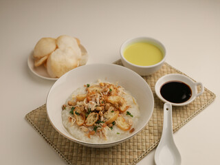 Rice porridge in a bowl, served with shredded chicken, chicken stock, fried shallot and crackers