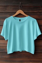A plain turquoise short-sleeve t-shirt mockup hanging on a wooden hanger against a rustic wooden background.
