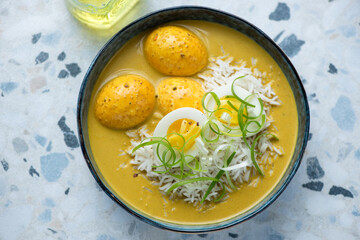 Bowl of egg curry with basmati rice, horizontal shot on a white and blue granite background, high angle view, selective focus