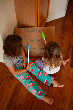 Big sister teaching sibling shapes at home