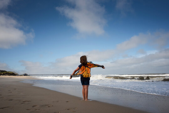 Young girl standing on beach wearing butterfly wings Avon Pier