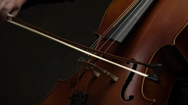 Closeup cello with bow, dark background. Musician playing classical music instrument. String instrument image for concert posters or album art.