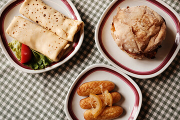 Traditional Balkan breakfast with pancakes, dessert kalach and bread sandwich with meat, cheese and vegetables. Top view.