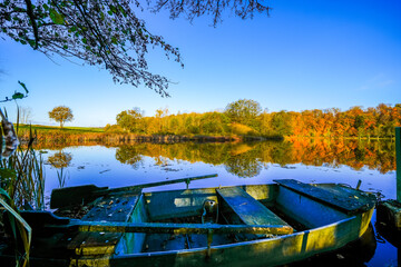 View of the autumn landscape at the Holzmaar near Gillenfeld. Idyllic nature by the lake in the Volcanic Eifel region of Rhineland-Palatinate.
