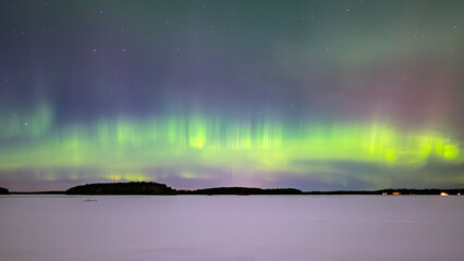 Northern lights dancing over lake in Farnebofjarden national park in north of Sweden
