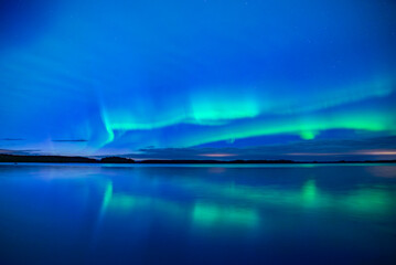 Northern lights dancing over lake in Farnebofjarden national park in north of Sweden
